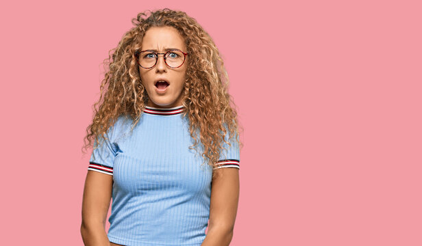 Beautiful caucasian teenager girl wearing casual clothes and glasses afraid and shocked with surprise expression, fear and excited face.