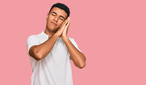 Young arab man wearing casual clothes sleeping tired dreaming and posing with hands together while smiling with closed eyes.
