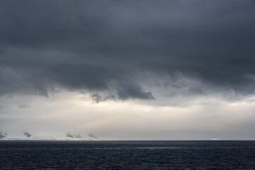 Stormy gray skies above the Southern Ocean with a sunbeam hitting the water, as a nature background 

