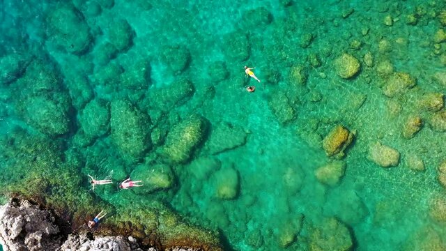 Aerial view of a young couple snorkeling above coral reef reaching deeper parts of the crystal clear water, Rhodes, Greece. Aerial drone view of a couple snorkeling swimming in crystal clear water.