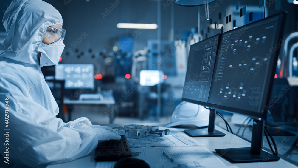 Poster modern factory: professional engineer in clean sterile coverall works on desktop computer, developin