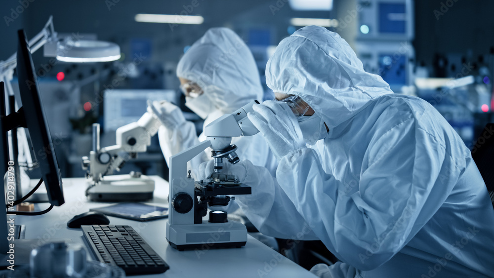 Fototapete research factory cleanroom: engineers / scientists wearing coveralls and gloves use microscopes to i