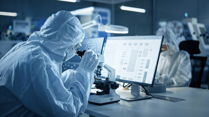 Research Factory Cleanroom: Team of Engineers and Scientists in Coveralls Work on Computers, Use...