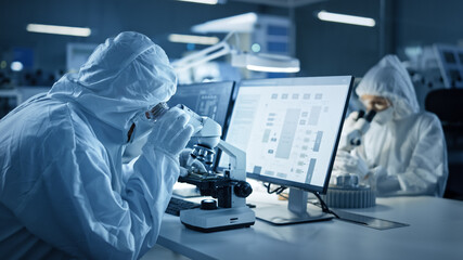 Modern Factory: Team of Engineers and Scientists in Clean Sterile Coveralls Work on Desktop...