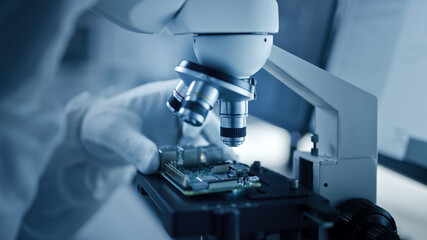Research Factory Cleanroom: Close-up of Engineer / Scientist wearing Coverall and Gloves Use Microscope to Inspect Motherboard Microprocessor Component, Developing High Tech Modern Electronics