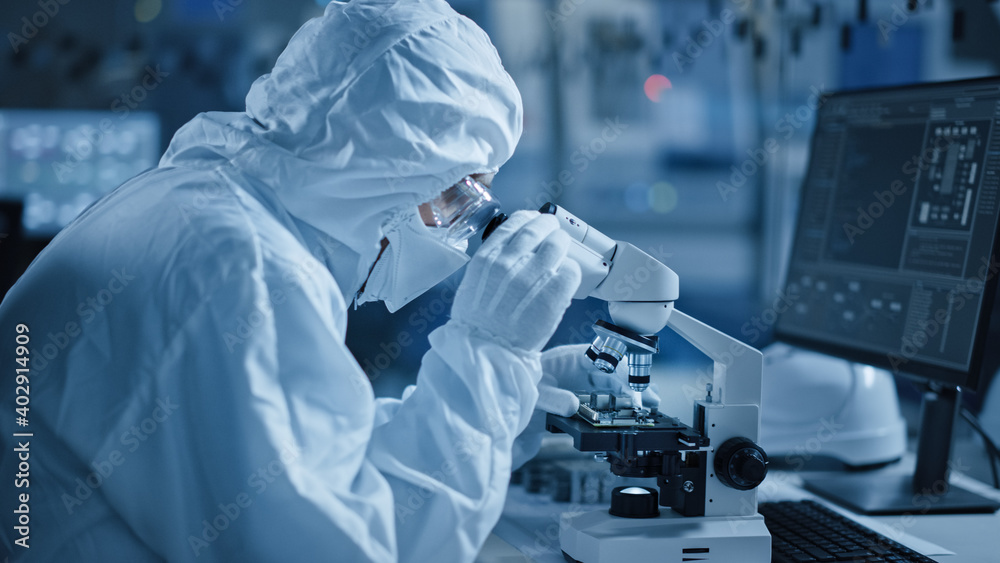 Poster research factory cleanroom: engineer / scientist wearing coverall, gloves uses microscope to inspect
