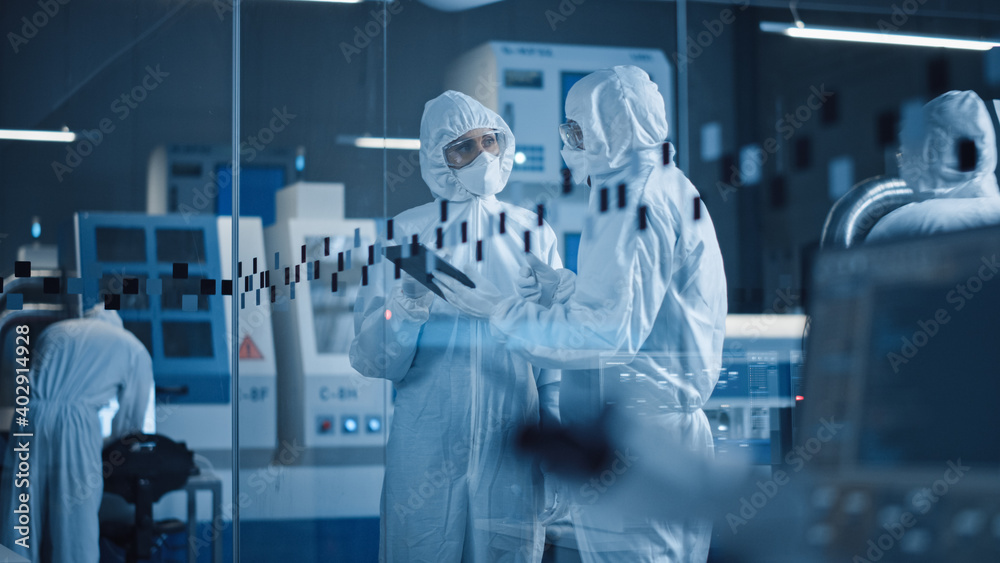 Poster factory cleanroom: engineer and scientist wearing coveralls, standing in workshop talk and use table
