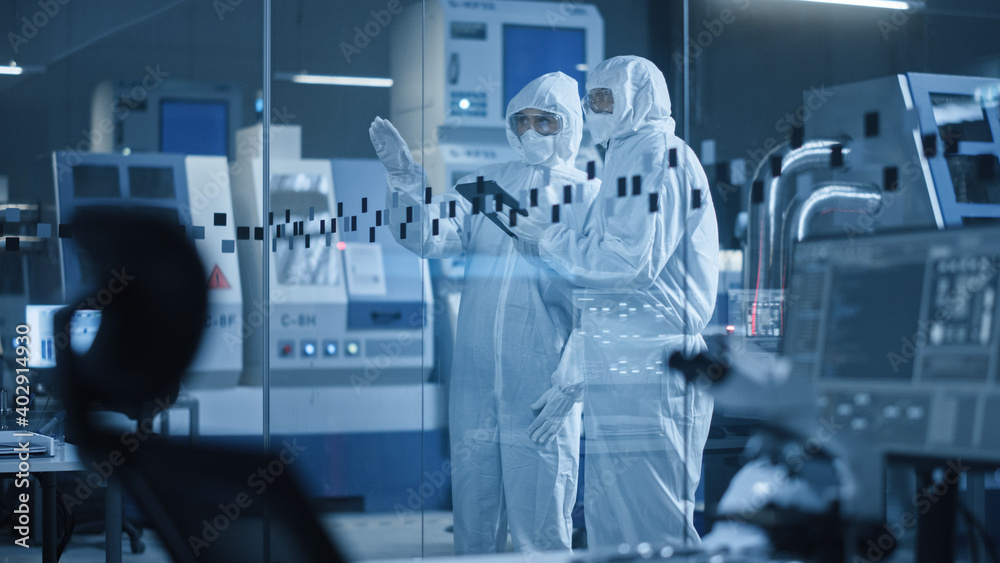 Poster factory cleanroom: engineer and scientist wearing coveralls, standing in workshop talk and use table