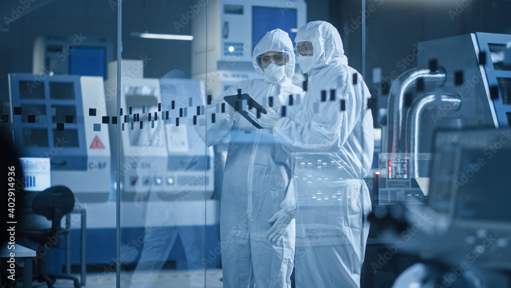 Poster factory cleanroom: engineer and scientist wearing coveralls, standing in workshop talk and use table