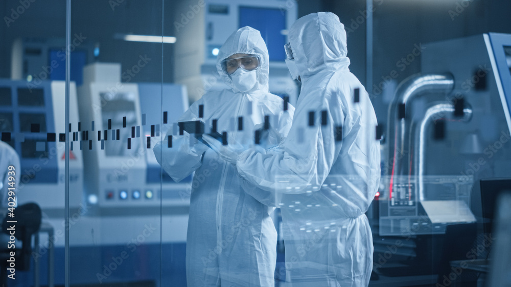 Poster factory cleanroom: engineer and scientist wearing coveralls, standing in workshop talk and use table