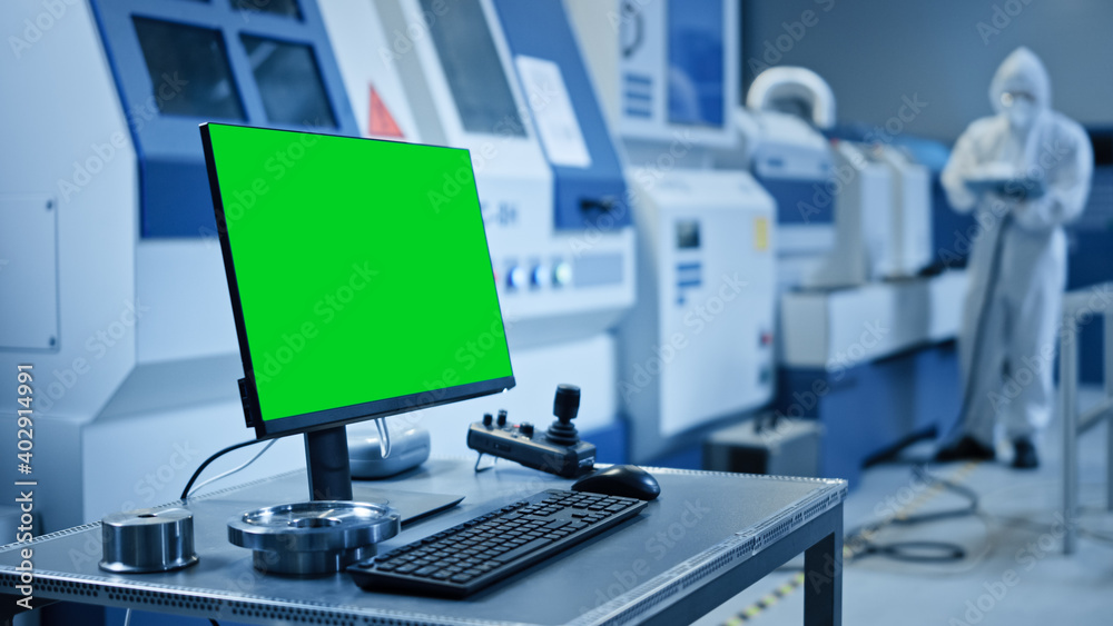 Poster Factory Cleanroom: On the Desk Personal Computer Showing Green Screen Chroma Key Display. In Background CNC Machinery, Professionals Use Robot Arm on Production Line.