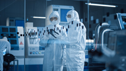 Research Factory Cleanroom: Engineer and Scientist Wearing Coveralls, Standing in Workshopop Talk...