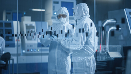 Factory Cleanroom: Engineer and Scientist Wearing Coveralls, Standing in Workshop Talk and Use...