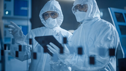 Factory Cleanroom: Engineer and Scientist Wearing Coveralls, Standing in Workshop Talk and Use...