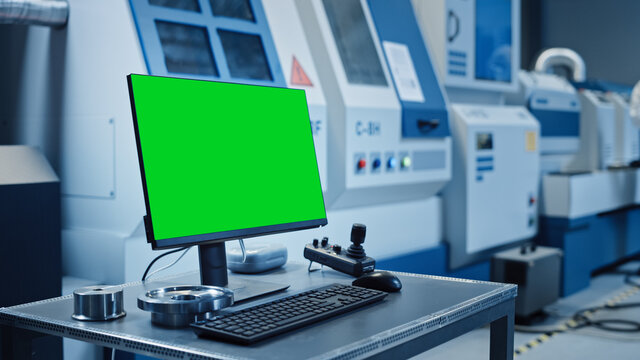 Factory Cleanroom: On the Desk Personal Computer Showing Green Screen Chroma Key Display. In Background CNC Machinery, Professionals Use Robot Arm on Production Line.