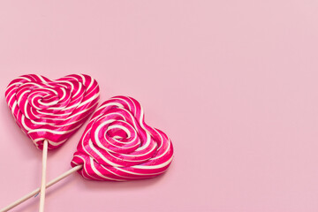 Two lollipops on a stick in the shape of a heart with a white bow close-up there is a place for text. Valentine's Day.