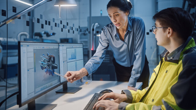In Factory: Professionals Working on CNC Machinery and Robot Arm Production Line. In-Office: Female Project Manager Talks to a Male Engineer Works on Computer Designing New Engine Prototype