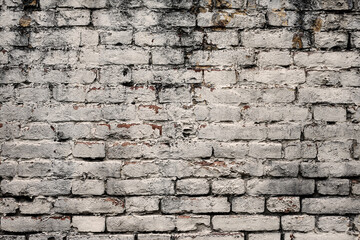 Aged white painted brick wall texture. Old textured grunge wall surface background pattern of masonry. Cracks and black stains.