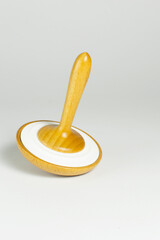 Wooden whirligig or spinning top toy for children on a gray background. Close-up. Vertical photo