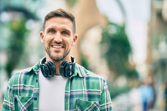 Young caucasian man smiling happy using headphones at the city.