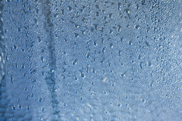 Large raindrops on the fogged glass, blue background.