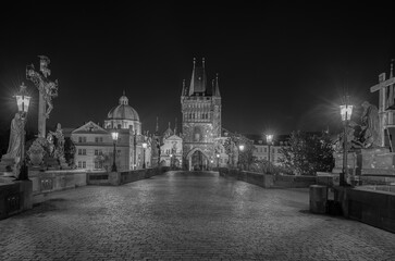 Obraz premium Empty Charles Bridge in the center of Prague during first wave of Covid-19 pandemy in the night with blue sky and yellow lights, Czechia, Europe