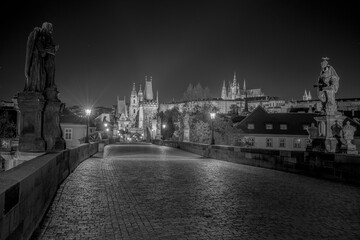 Obraz premium Empty Charles Bridge in the center of Prague during first wave of Covid-19 pandemy in the night with blue sky and yellow lights, Czechia, Europe