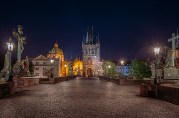 Fototapeta na wymiar Empty Charles Bridge in the center of Prague during first wave of Covid-19 pandemy in the night with blue sky and yellow lights, Czechia, Europe