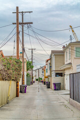 Fototapeta na wymiar Narrow road along houses in Long Beach California neighborhood with cloudy sky