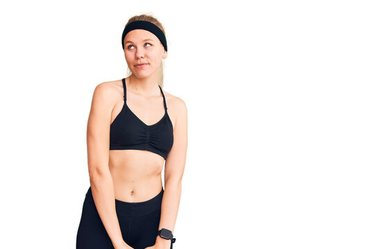 Young beautiful blonde woman wearing sportswear smiling looking to the side and staring away thinking.