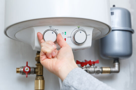 Female hand turning on electric water heater (boiler).