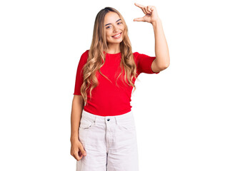 Obraz na płótnie Canvas Young beautiful blonde woman wearing casual clothes smiling and confident gesturing with hand doing small size sign with fingers looking and the camera. measure concept.