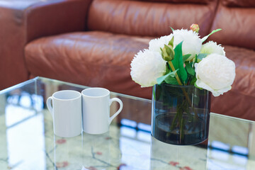 Two cups of tea or coffee together on a coffee table in a light home interior room