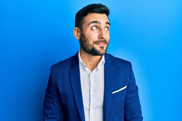 Young hispanic businessman wearing business jacket smiling looking to the side and staring away thinking.