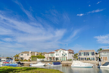 Fototapeta na wymiar Serene blue sky over houses overlooking boats at the harbor in Huntington Beach