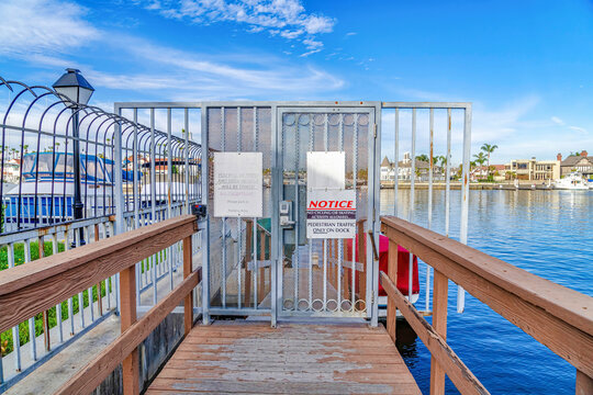 Warning signs and notices at the gate of a dock in Huntington Beach neighborhood