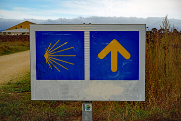 Wegeschild für den Jakobsweg, links das Symbol für die Muschel, rechts der Pfeil, der zeigt in welche Richtung es weitergeht. 