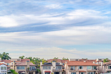 Fototapeta na wymiar Houses and palm trees against a cloudy skyscape in Huntington Beach California