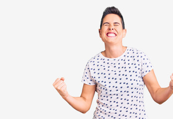 Young woman with short hair wearing casual clothes very happy and excited doing winner gesture with arms raised, smiling and screaming for success. celebration concept.