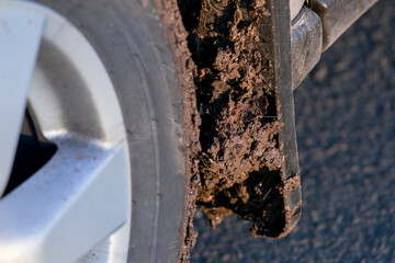 dirty car mudflap on the front wheel splashed with a mud closeup, tire with disk on a suv 4x4, nobody.
