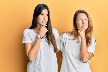 Hispanic family of mother and daughter wearing casual white tshirt thinking worried about a question, concerned and nervous with hand on chin