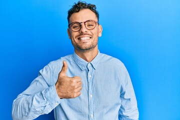Young hispanic man wearing casual clothes and glasses doing happy thumbs up gesture with hand....