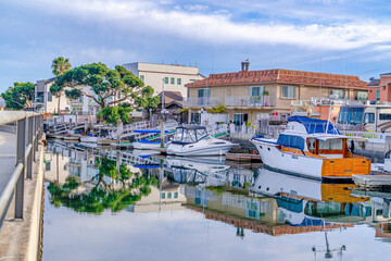 Fototapeta na wymiar Boats and yachts on docks of canal along road and houses in Huntington Beach