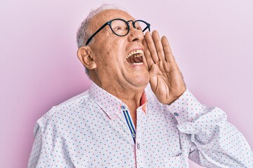 Senior caucasian man wearing casual clothes and glasses shouting and screaming loud to side with hand on mouth. communication concept.