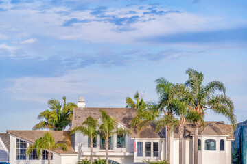 Fototapeta na wymiar Luxury house exterior view and tall palm trees against blue sky with clouds