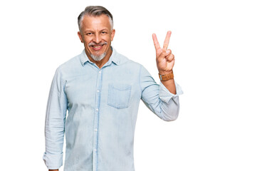 Middle age grey-haired man wearing casual clothes showing and pointing up with fingers number two while smiling confident and happy.