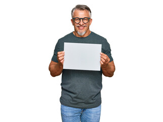 Middle age grey-haired man holding blank empty banner looking positive and happy standing and...