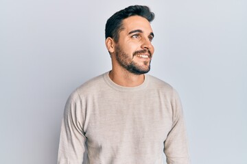 Young hispanic man wearing casual clothes looking to side, relax profile pose with natural face and confident smile.