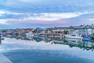Boats and yachts on scenic harbor water that reflects the cloudy sky at sunset