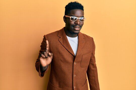 Handsome black man wearing elegant clothes and glasses smiling with an idea or question pointing finger up with happy face, number one